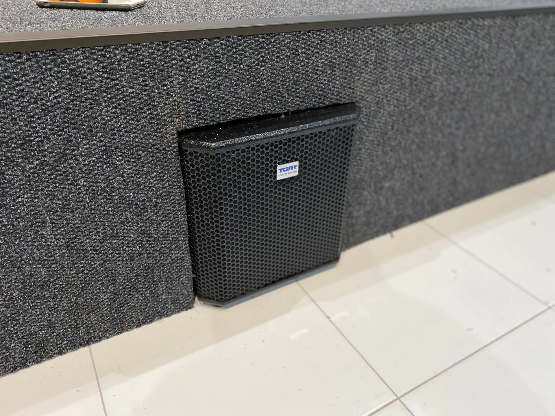 Ambiente corporativo — Caixa embutida em parede com tratamento acústico, sonorização discreta por zona.